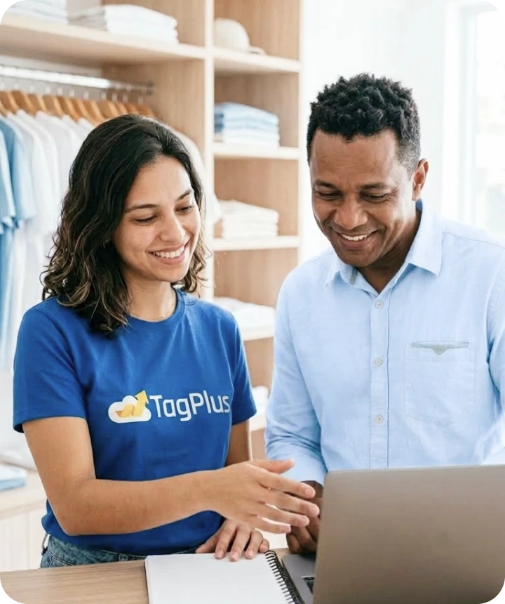 Profissional da TagPlus mostrando o sistema no notebook para um lojista sorridente, em loja organizada